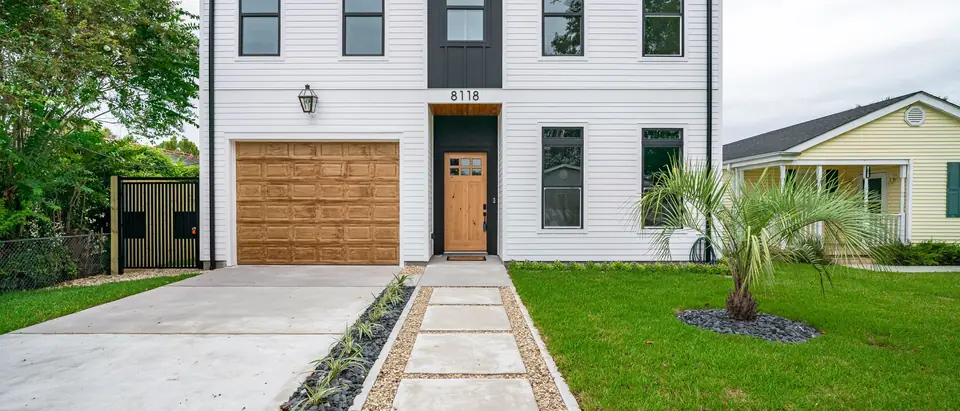 A white two-story house with a wooden garage door and a new driveway