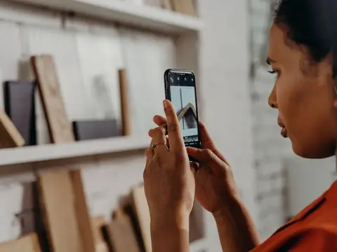 A woman photographing old shelves and wood boards with her phone