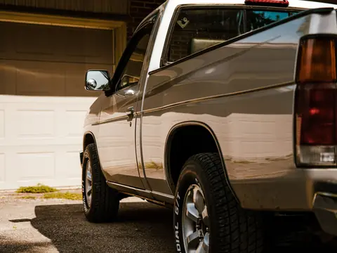 A clean pickup truck parked in the sun in front of a garage door