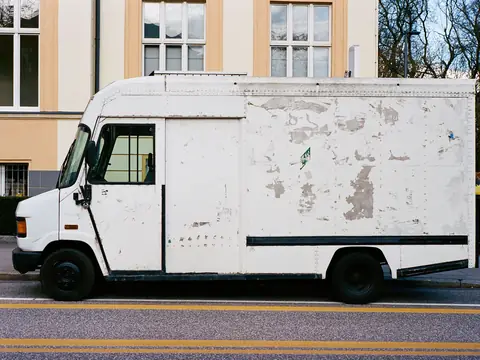 A plain white box truck parked on a sunny street